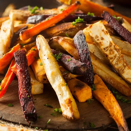 carrot and beet keto fries sprinkled with parsley on a wooden board